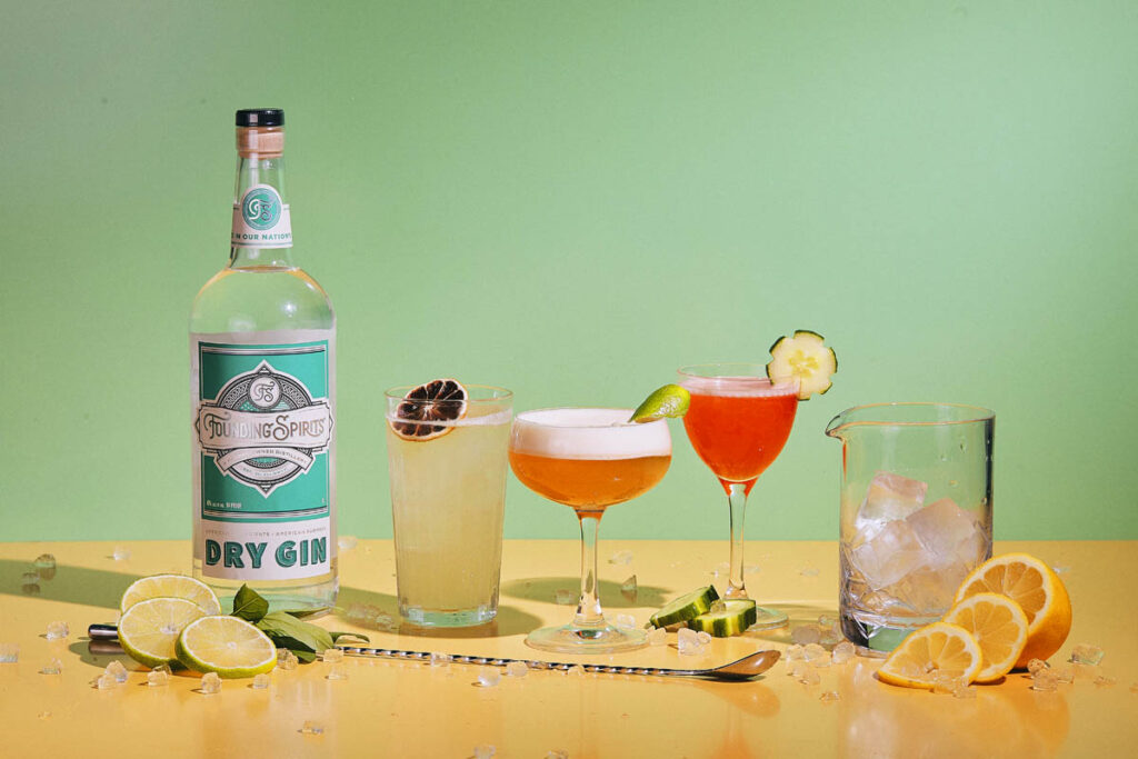Award-winning Founding Spirits Dry Gin displayed alongside three vibrant craft cocktails garnished with citrus and cucumber, celebrating a Best of DC win with a colorful, refreshing presentation.